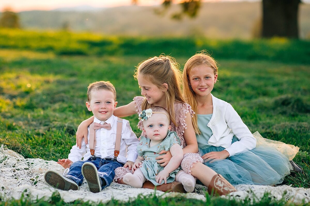Brother and sisters sitting on a blanket in a field in the Shenandoah Valley