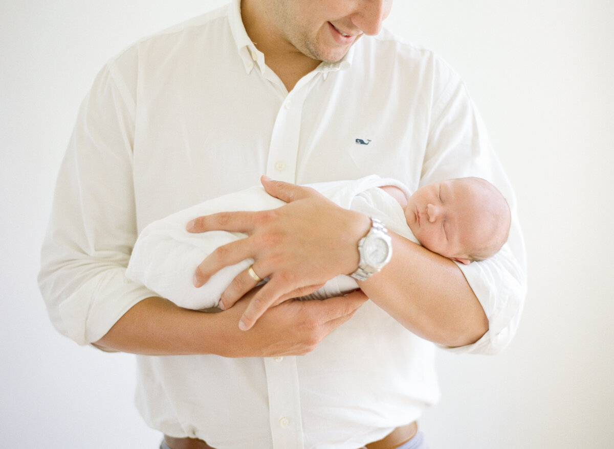 Dad holds newborn son during a Youngsville NC newborn photography session. Photographed by Raleigh Newborn Photographer A.J. Dunlap Photography.