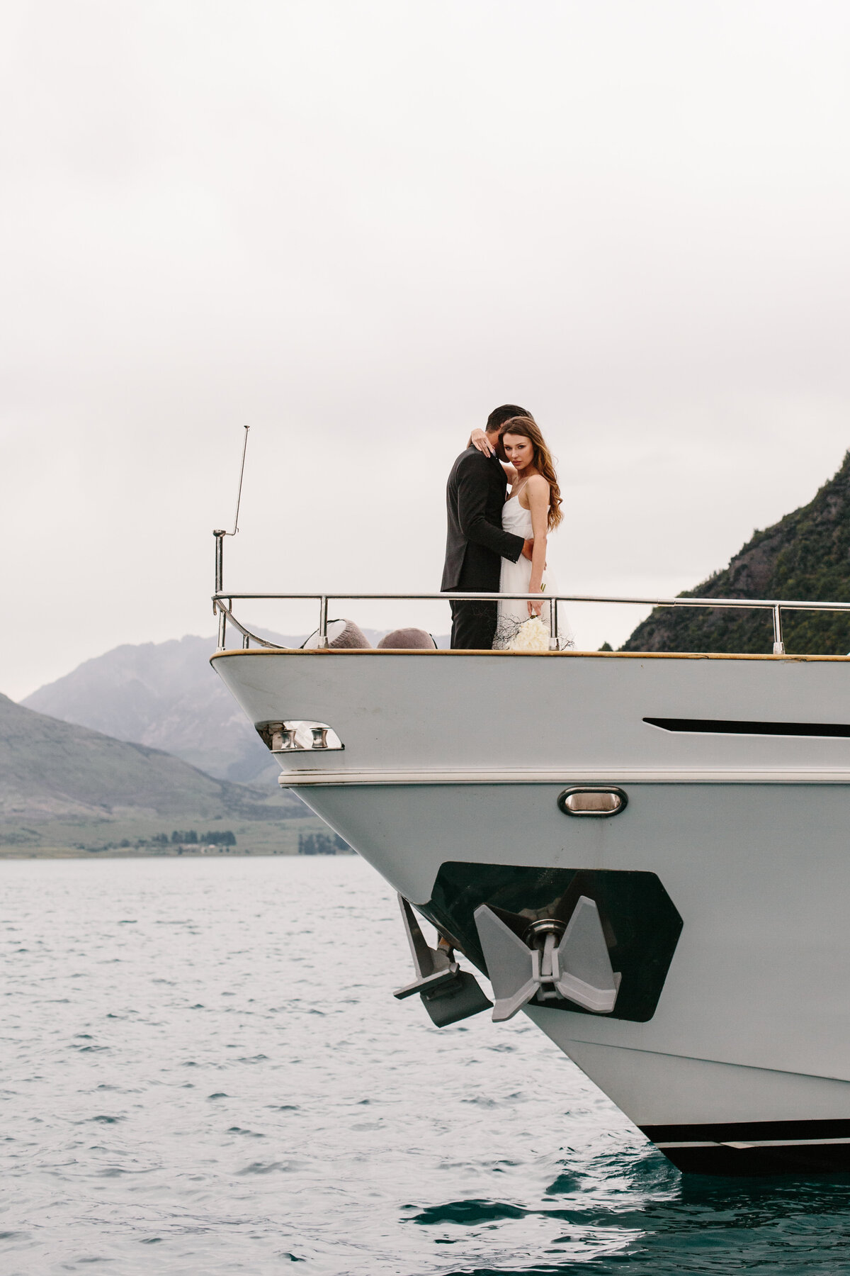 The Lovers Elopement Co - wedding photography - bride and groom embrace on boat sailing on Queenstown lake