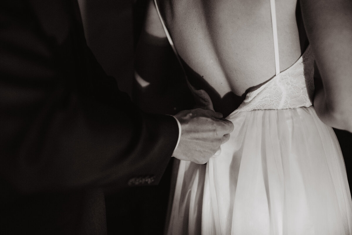 Utah elopement photographer captures groom buttoning bride's dress before National Parks Wedding