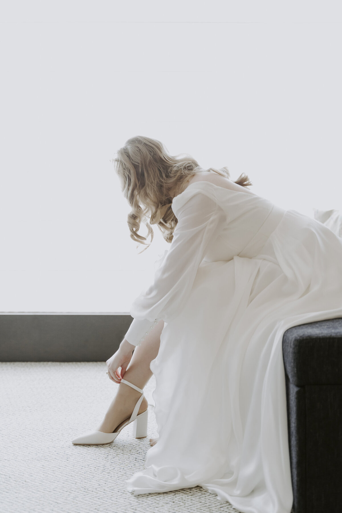the bride is sitting down while putting on her white heels in grand hyatt hotel in seoul