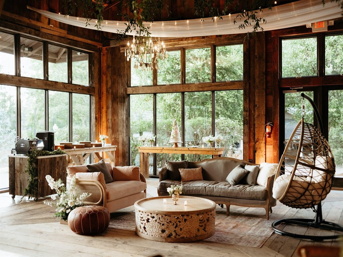Warm and inviting lounge space surrounded by windows overlooking trees and lake at Hudson Valley wedding venue Cedar Lakes Estate