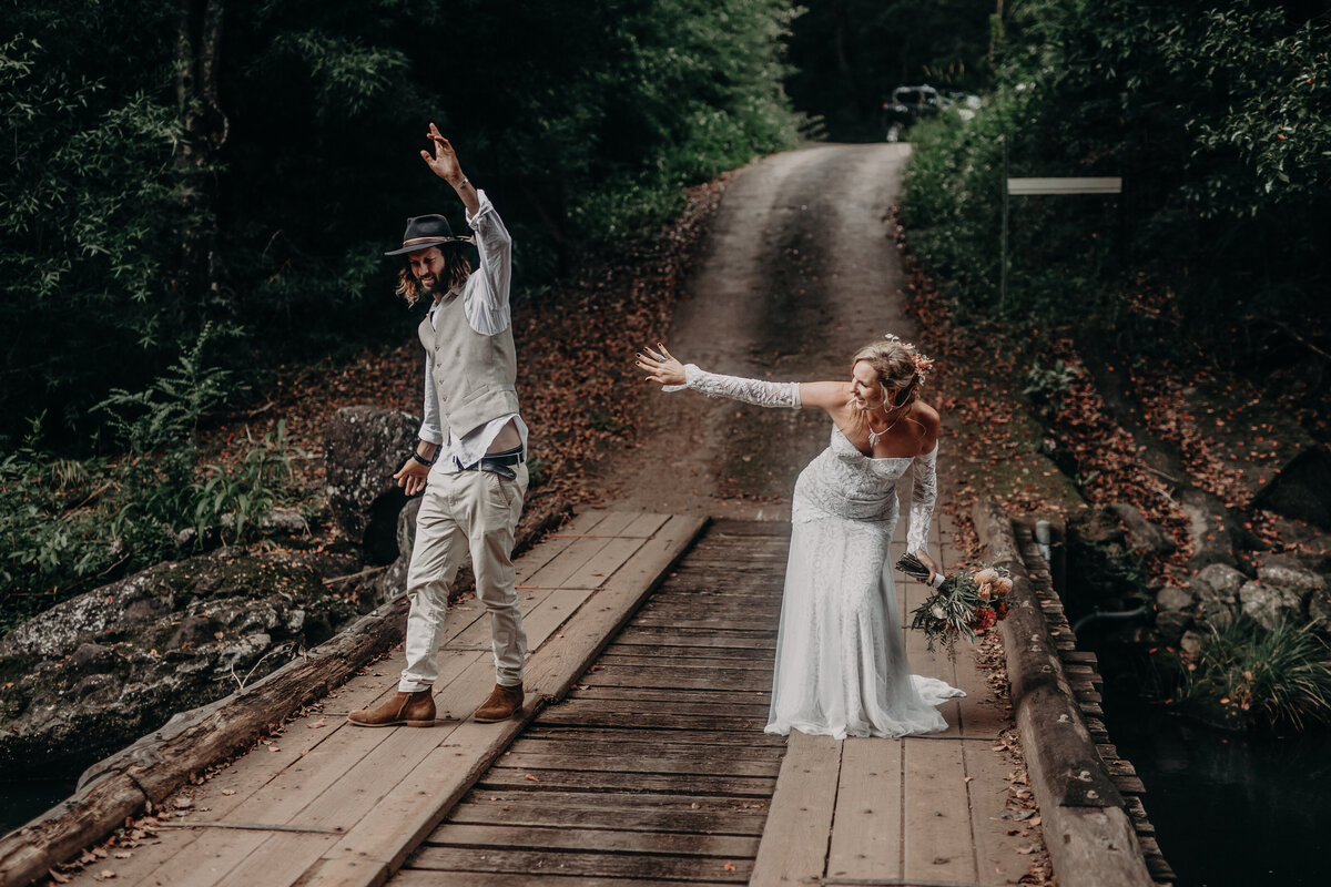 Bride and groom captured from a distance on a wooden bridge in a forest