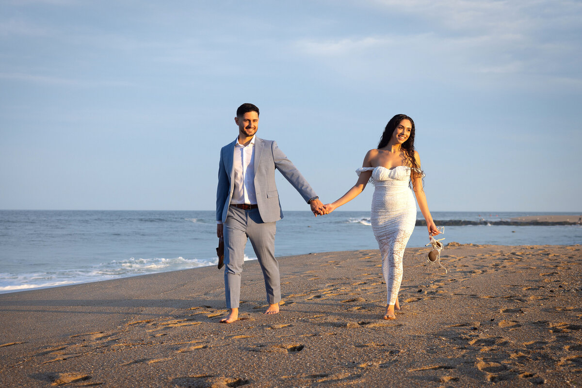 engaged-couple-walking-in-sand-asbury-park-beach