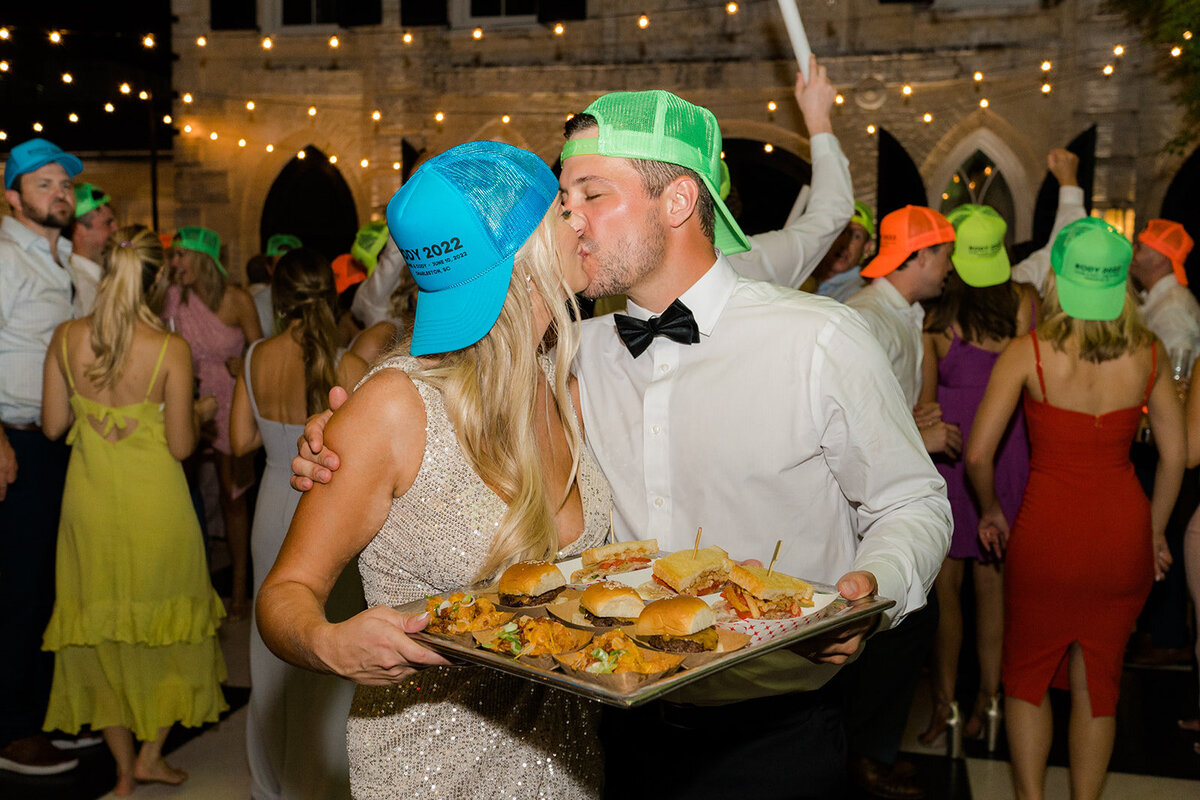 Bride and groom in neon hats holding Pittsburgh themed late night bites. William Aiken House spring wedding reception. Kailee DiMeglio Photography.