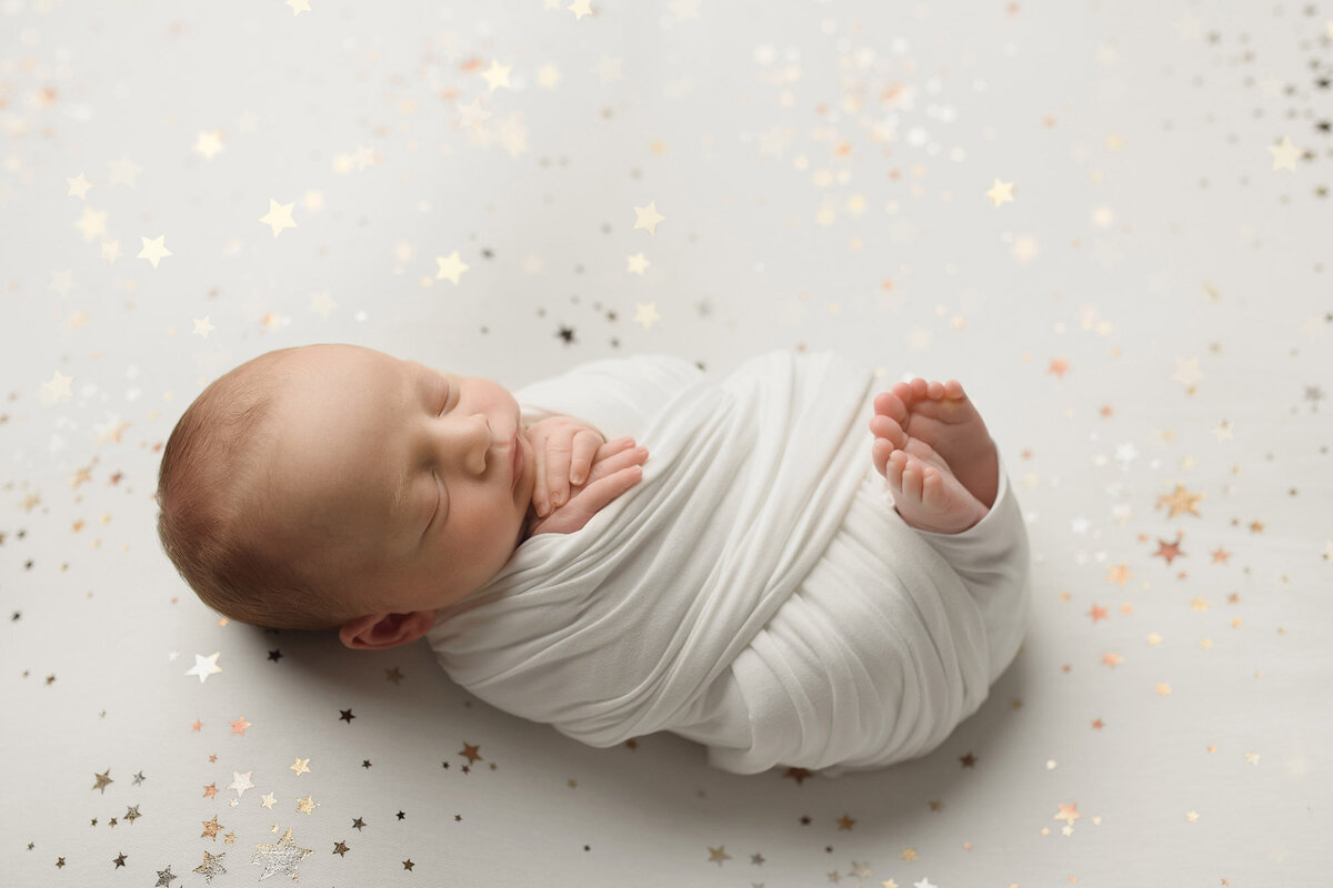 Swaddled newborn baby on star backdrop