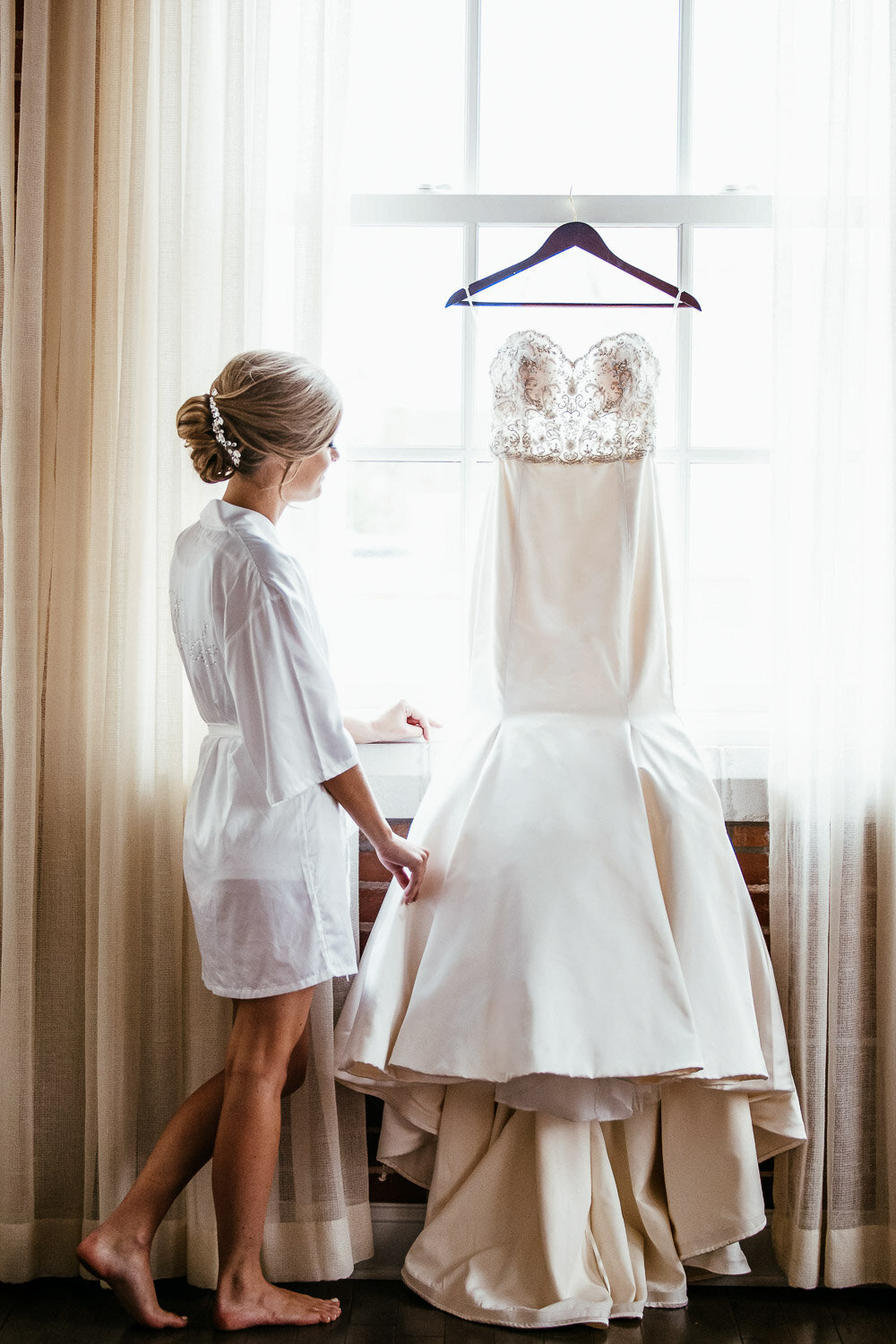Bride looking at her hung up wedding dress