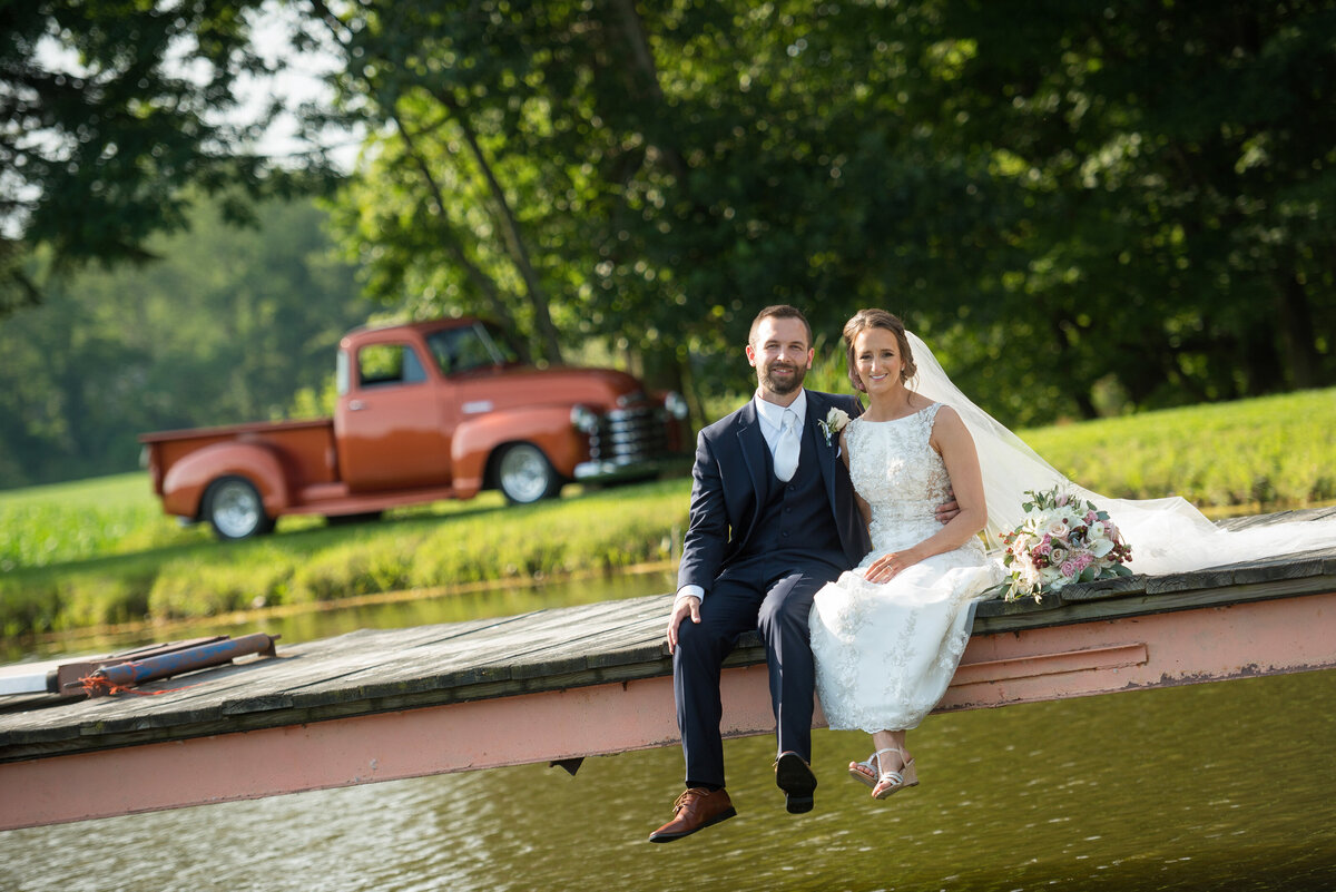 Bride and groom sitting with a vintage truck.