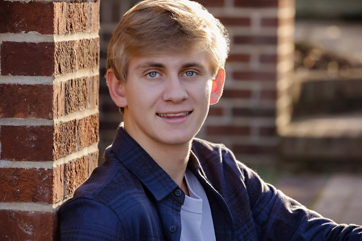 Handsome teen seated on brick terrace steps surrounded by autumn foliage at UNCC Botanical Garden Charlotte NC