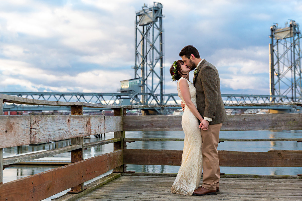 The newly eloped couple kiss in front of the Memorial Bridge in Portsmouth New Hampshire