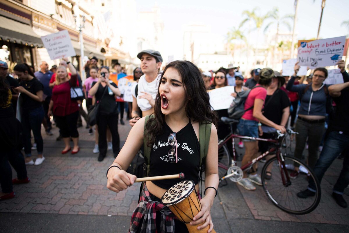 Young women beats drum and chants at protest downtown San Diego