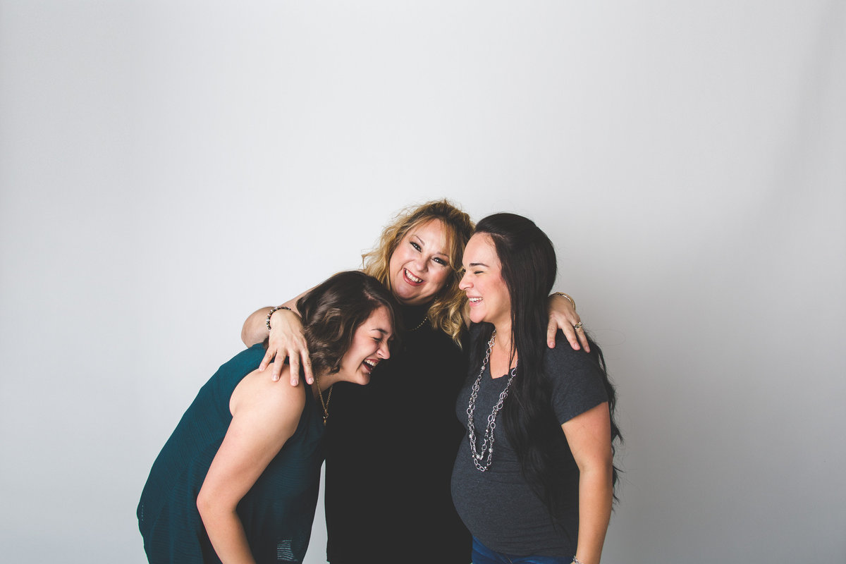 mother and daughters laughing in studio for mothers day portrait