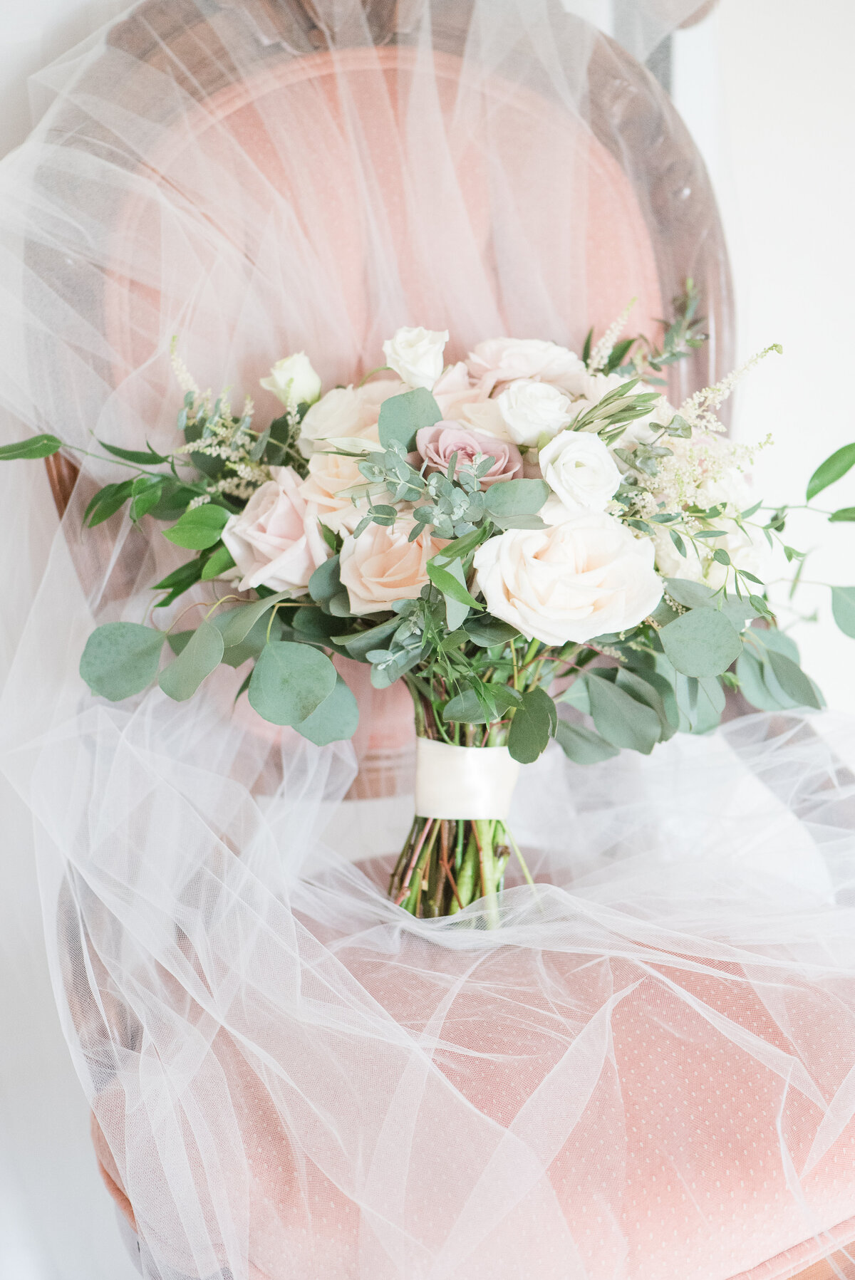 bridal bouquet on pink velvet vintage chair and veil