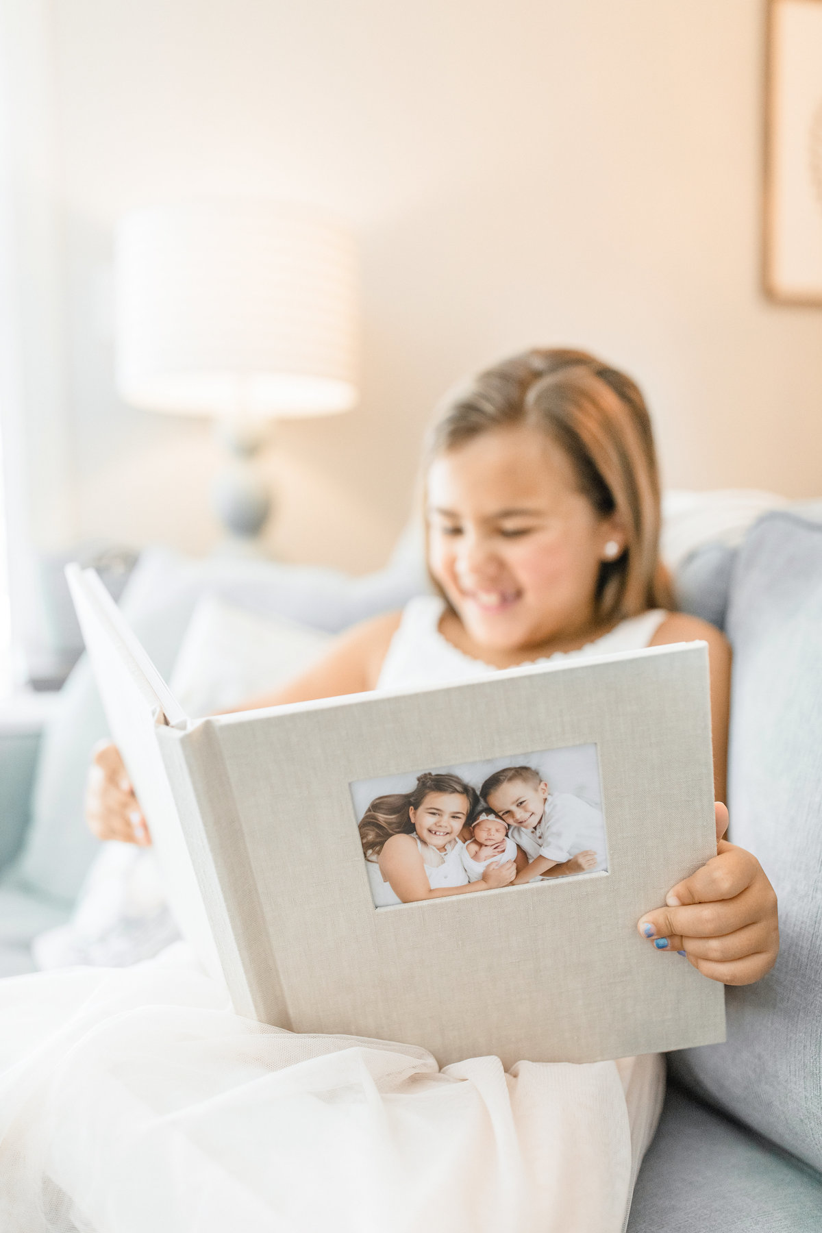 girl holding album from newborn session in Miami by Ivanna Vidal Photography