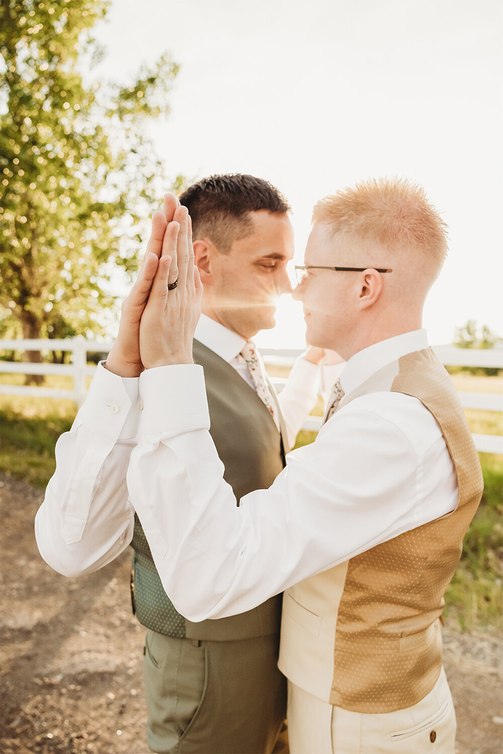 Grooms touching hands with sunlight shining between them at a Mountain Sage Wedding, Camelot Ranch.