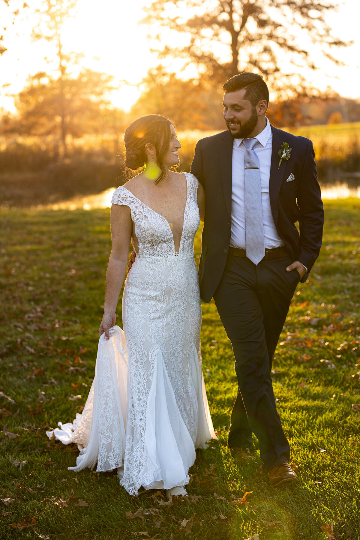 Bride and groom walk and laugh during golden hour portraits