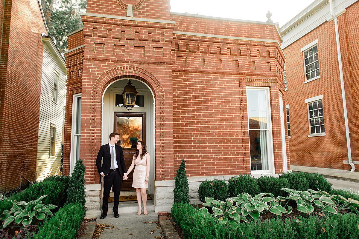 Engaged couple standing under historic brick building in downtown Franklin