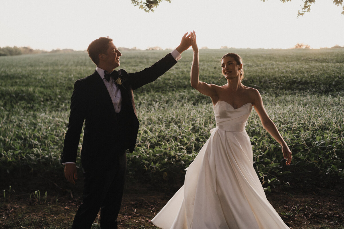 Bride and groom dancing in a field