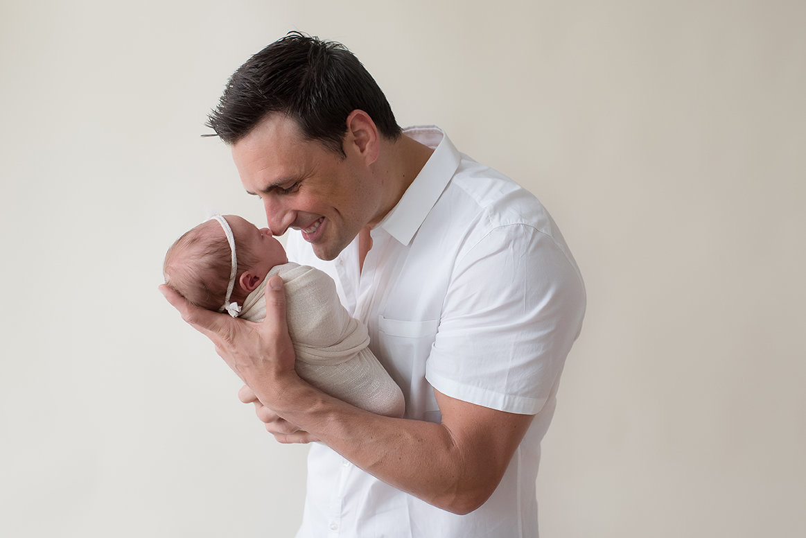 a dad holds his new daughter in the studio