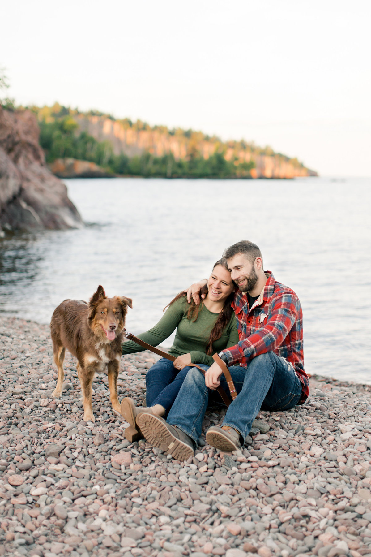 dog and couple on the pebble beach of minnesota north shore state park with lake superior in the backgrond