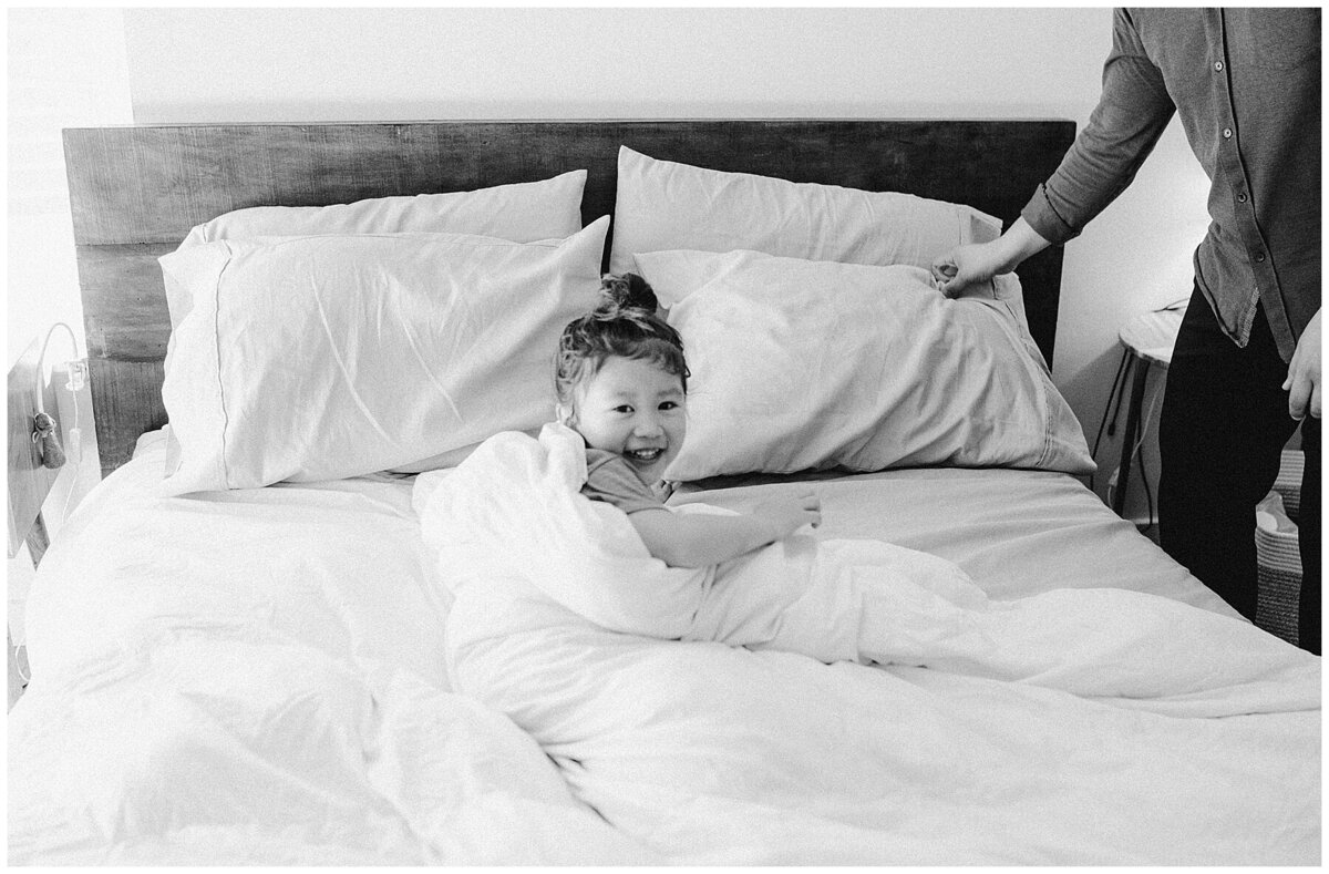 Young child on a bed laughing at family photo session in Austin by Amber Vickey Photography