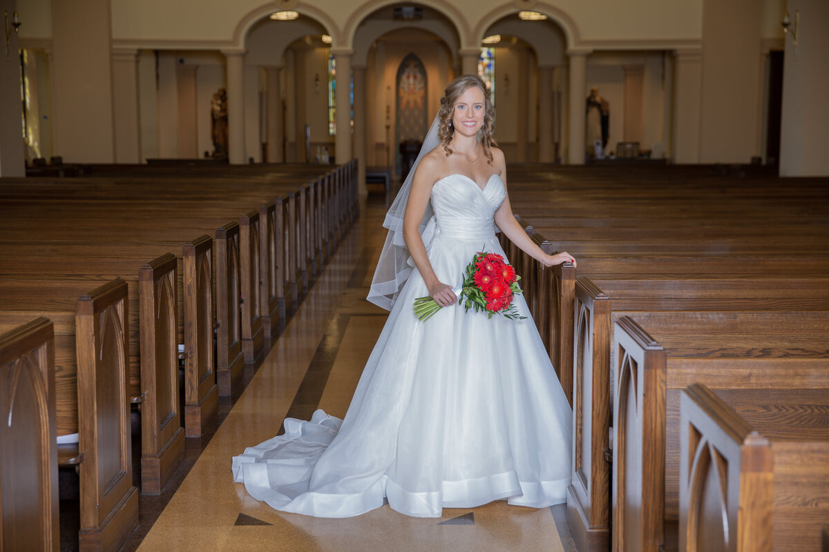 Bride poses in church aisle