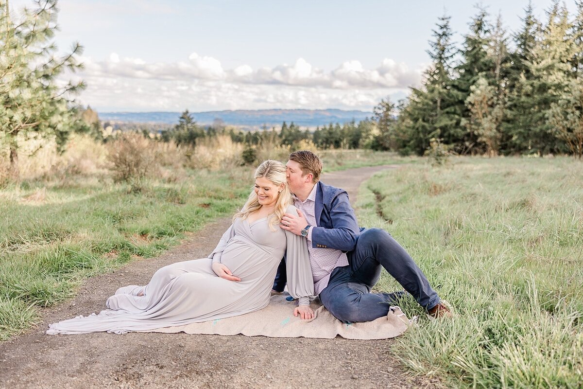 Husband kissing pregnant wife's head in maternity photo session near portland