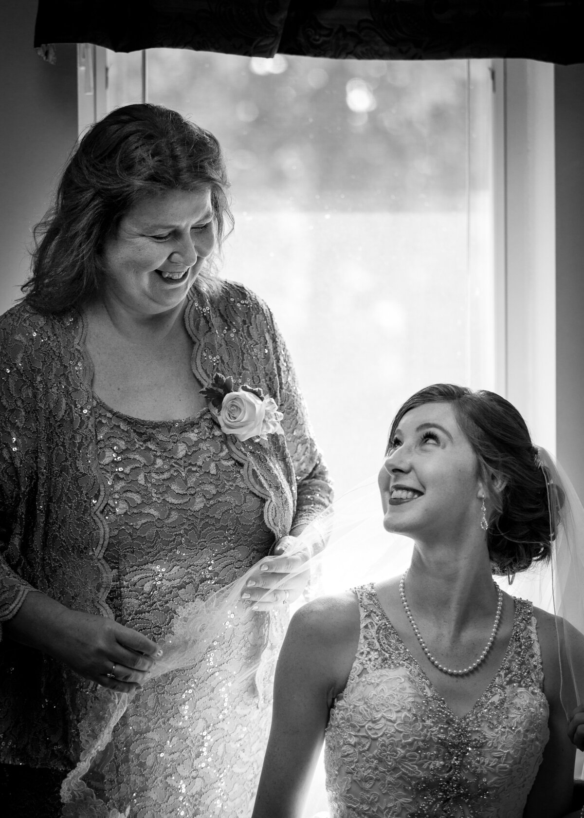 black and white image of bride looking up at her mother on wedding day