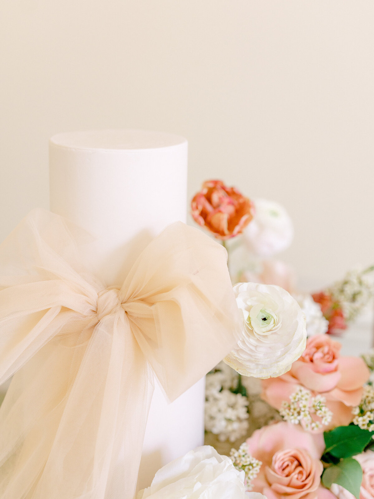 Close up of a tied bow next to a pink and white floral arrangement