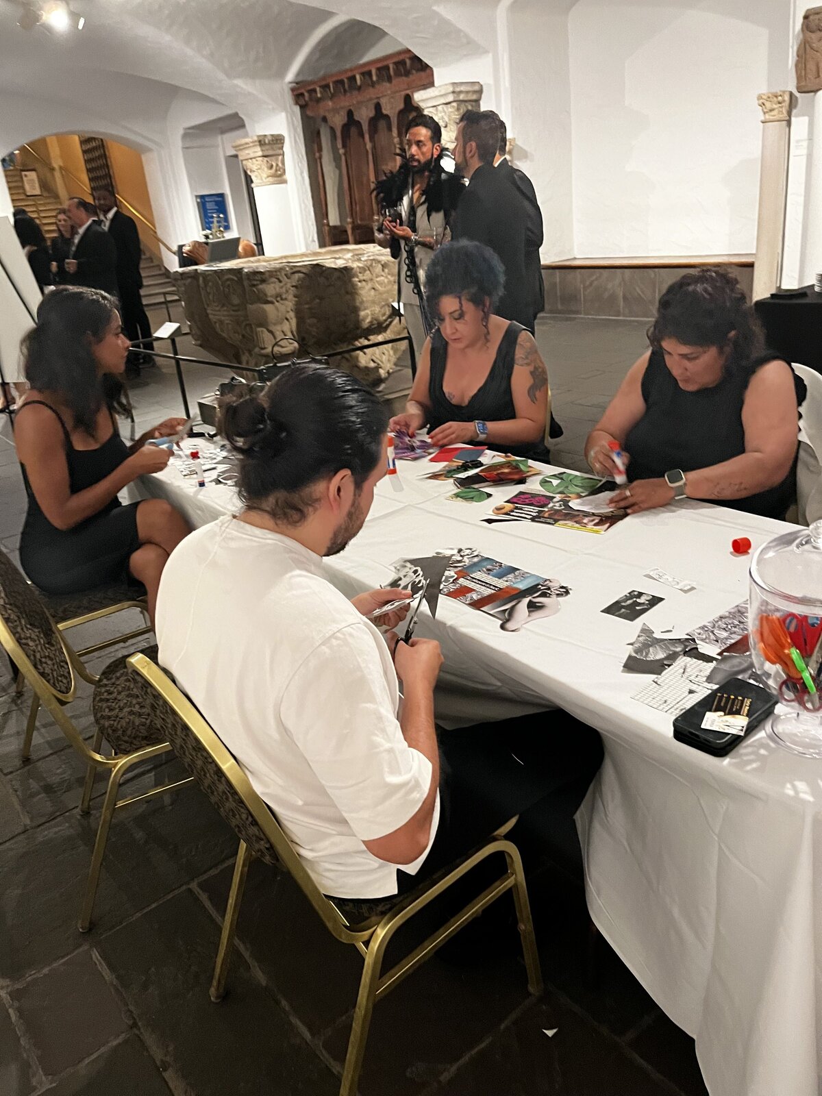 People sitting at a table working on their collage - cutting images, gluing, and arranging