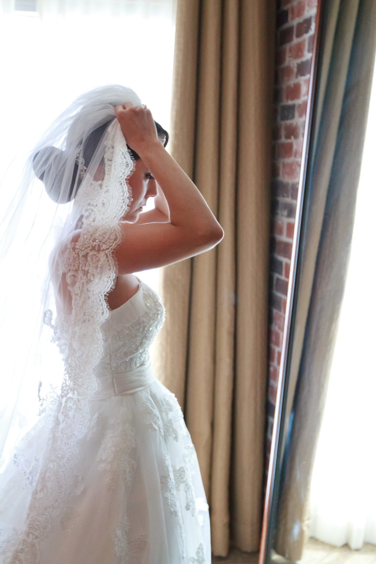 Bride putting on her veil getting ready at the Hotel Contessa for her same sex wedding in downtown San Antonio