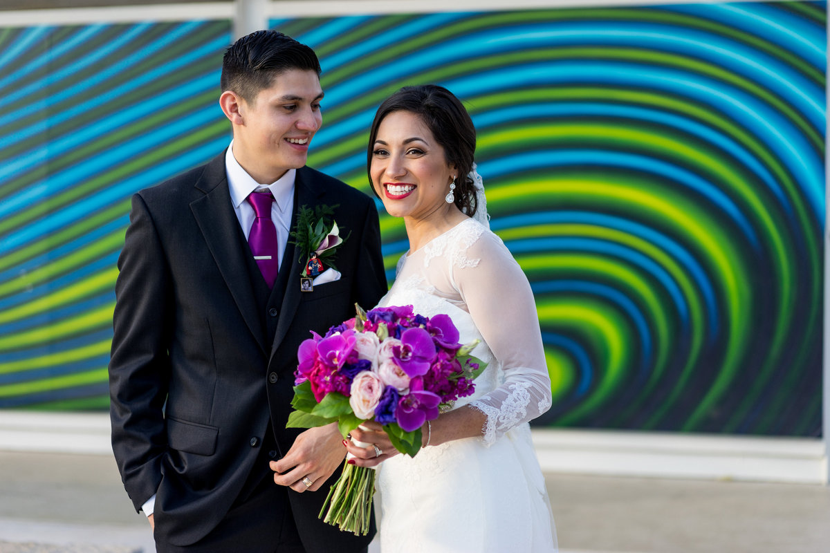 bride and groom sitting in front of art at Hemisfair in downtown San Antonio by the Tower of the Americas
