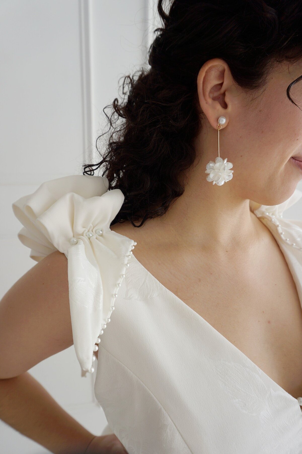 Close-up of the pearl embellished shoulder ruffles and floral crepe fabric on the Taylor wedding dress style.