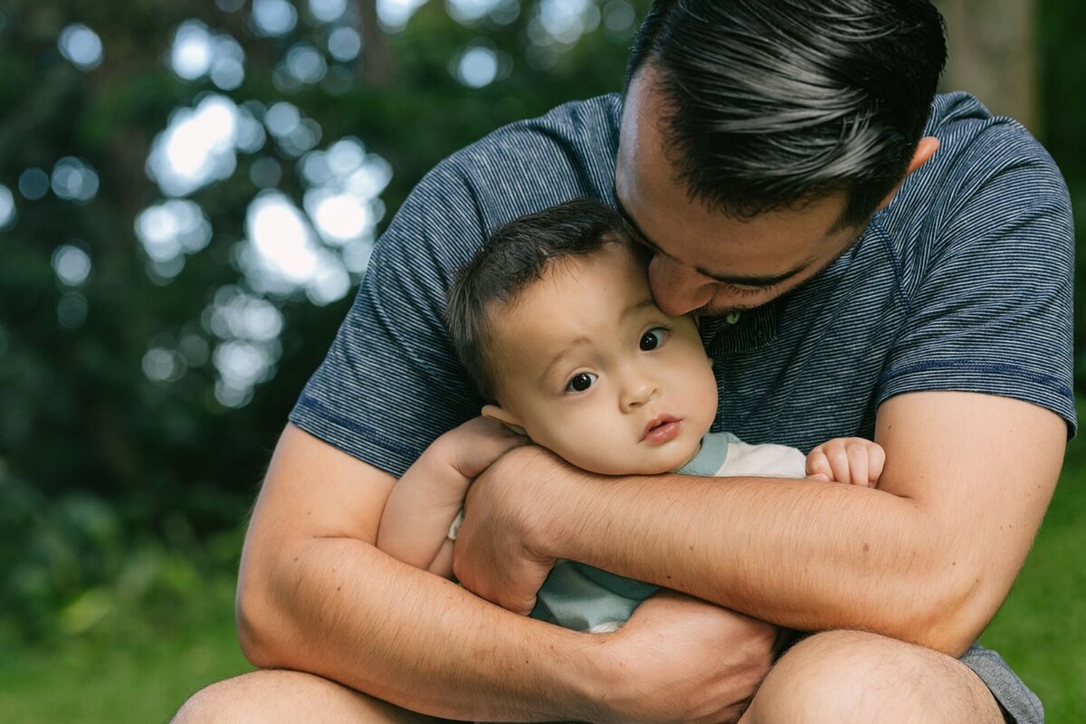 dad engulfs baby in a bear hug during oahu photo shoot