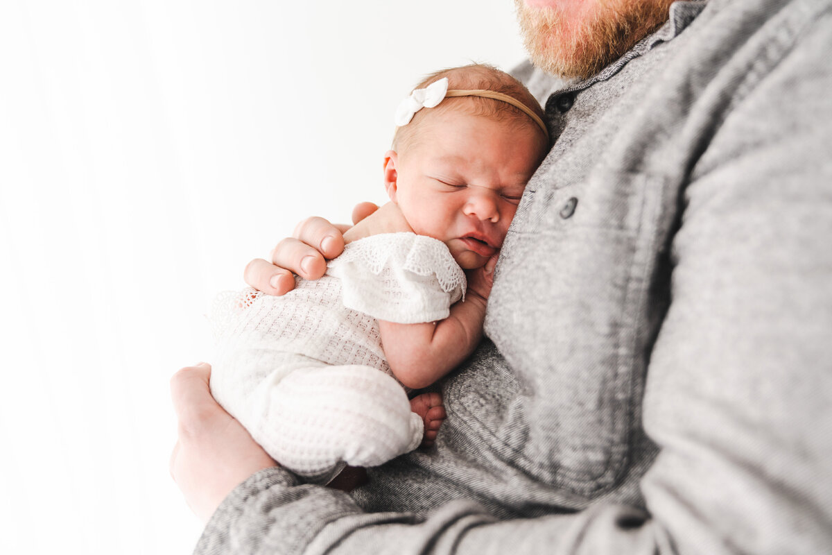 Baby girl snuggling in dad's chest, taken by Fig and Olive Photography a Twin Cities Newborn Photographer