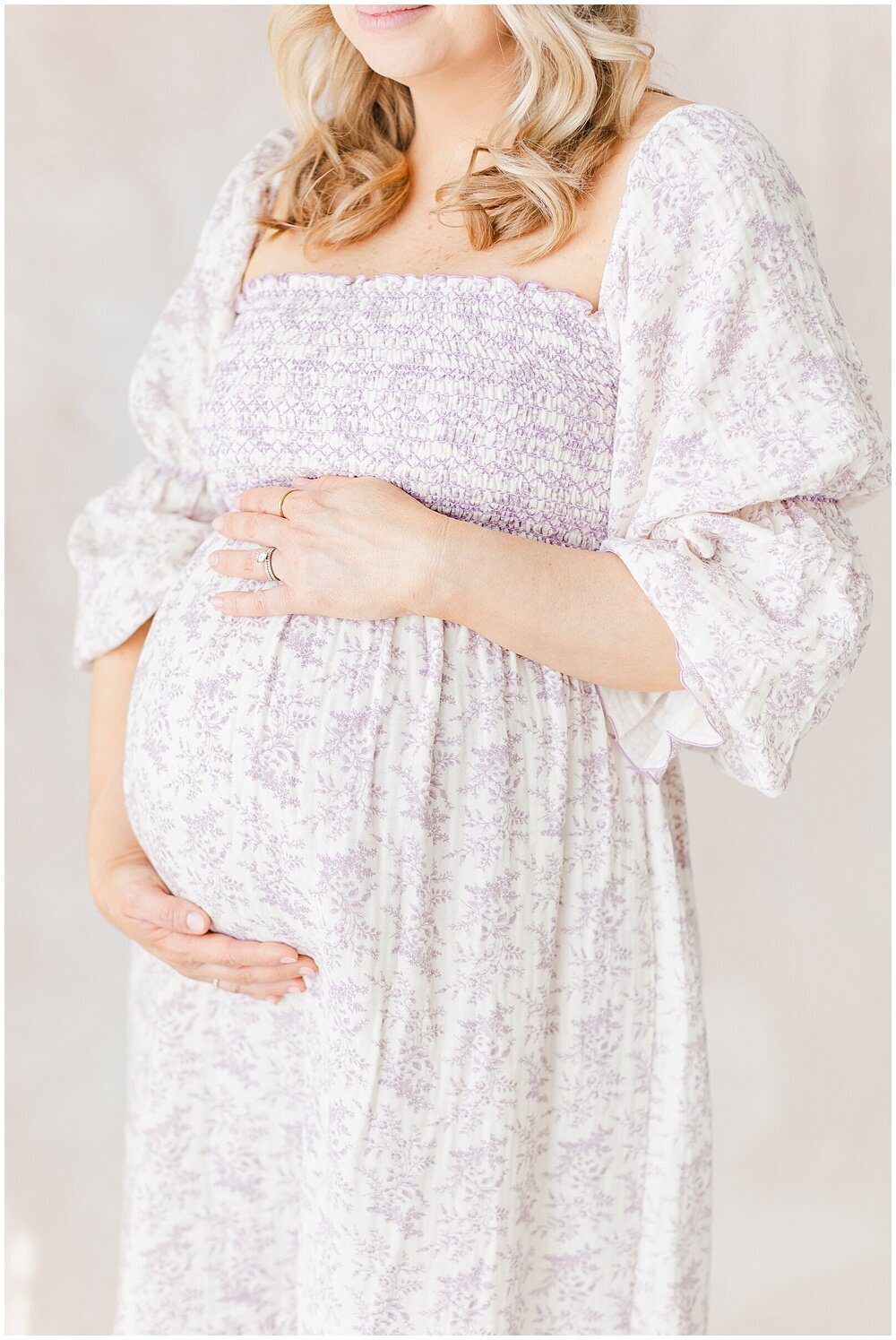 A pregnant mother holding her pregnant belly in front of a hand-painted canvas backdrop by northern virginia newborn photographer
