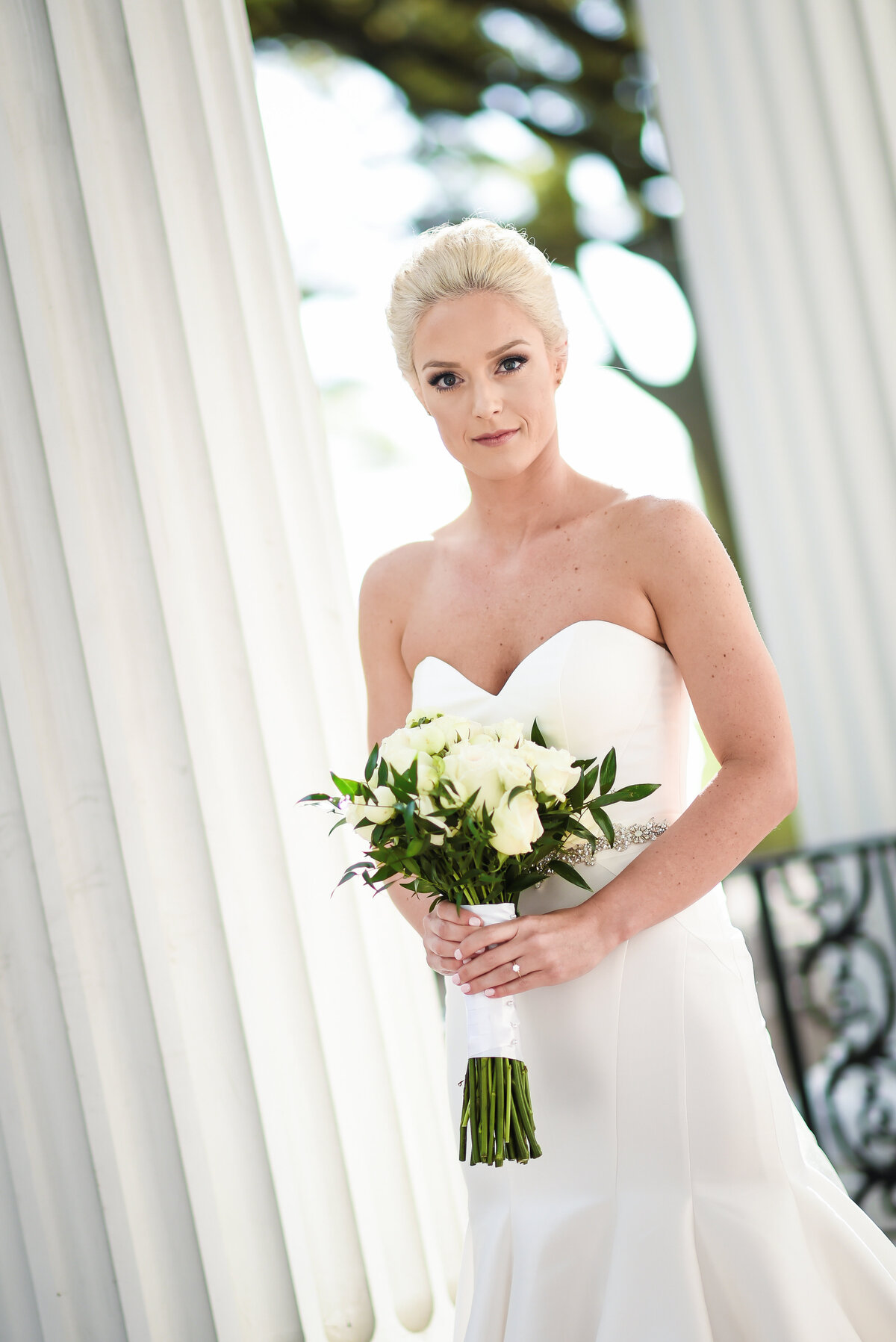 Beautiful bridal portrait photography: bride stands among the columns with white bouquet at First Presbyterian in Biloxi, MS