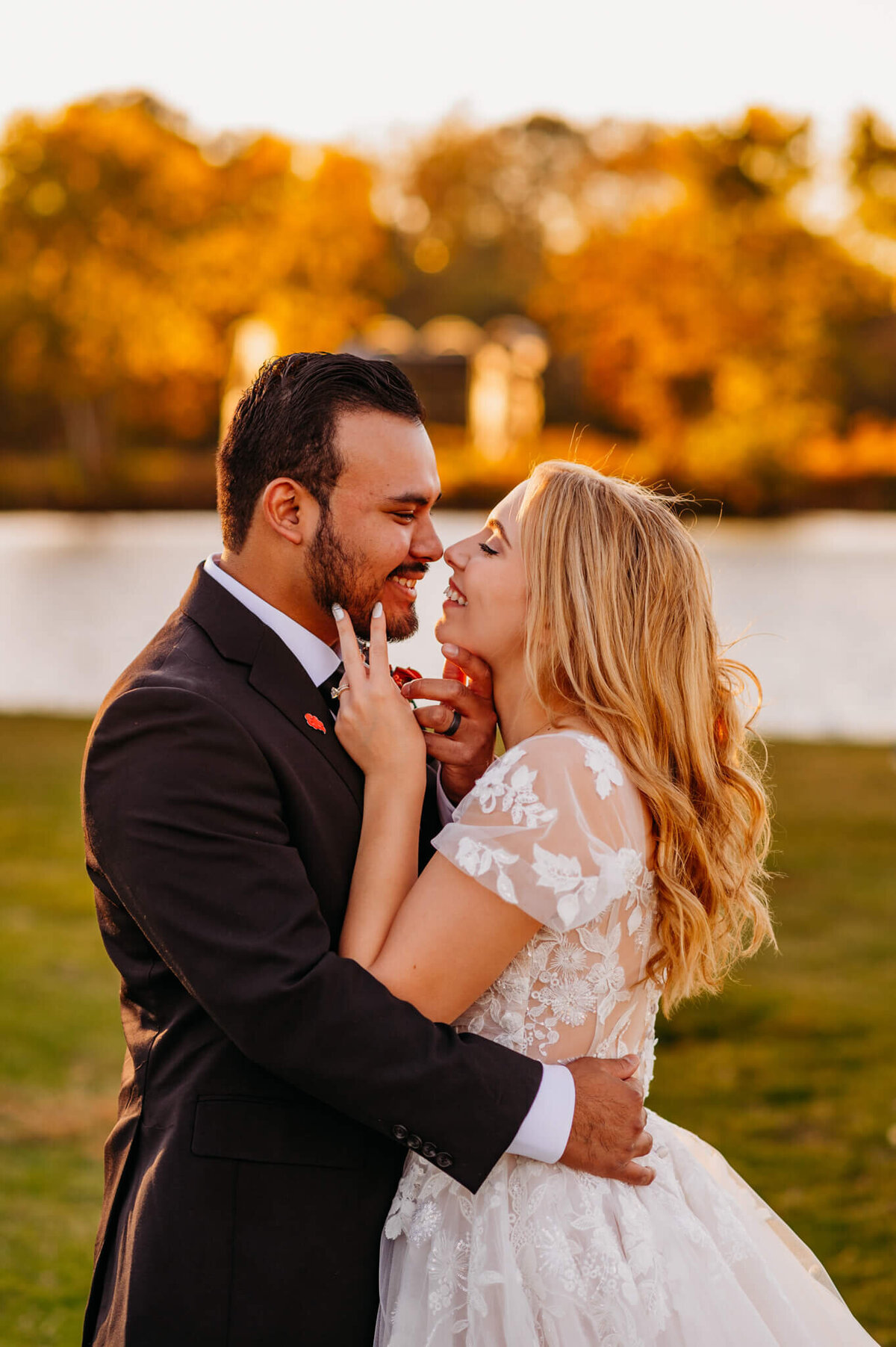 photo of a bride and groom holding each others' faces and smiling at each other