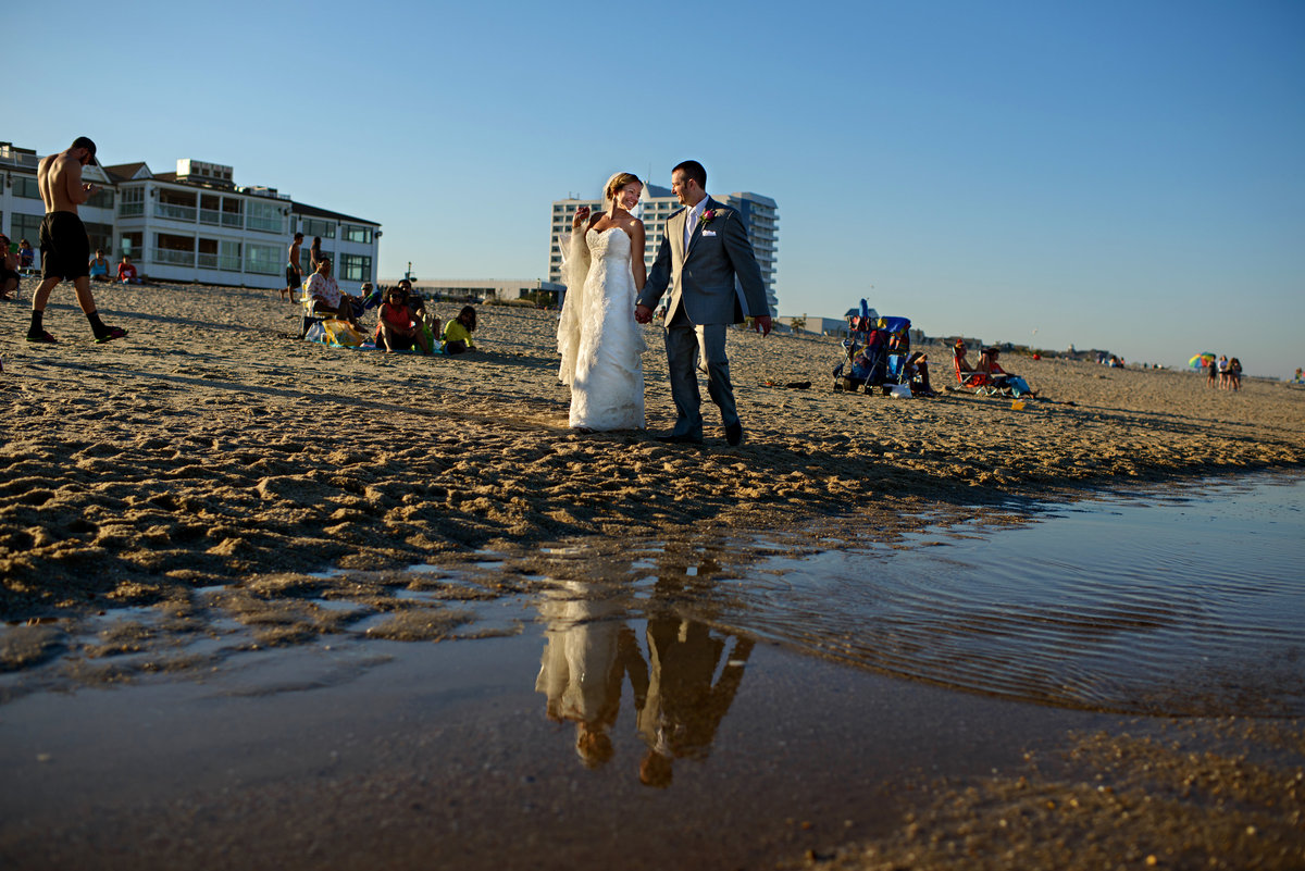 A newly married couple walk along the beach after their long branch NJ wedding.
