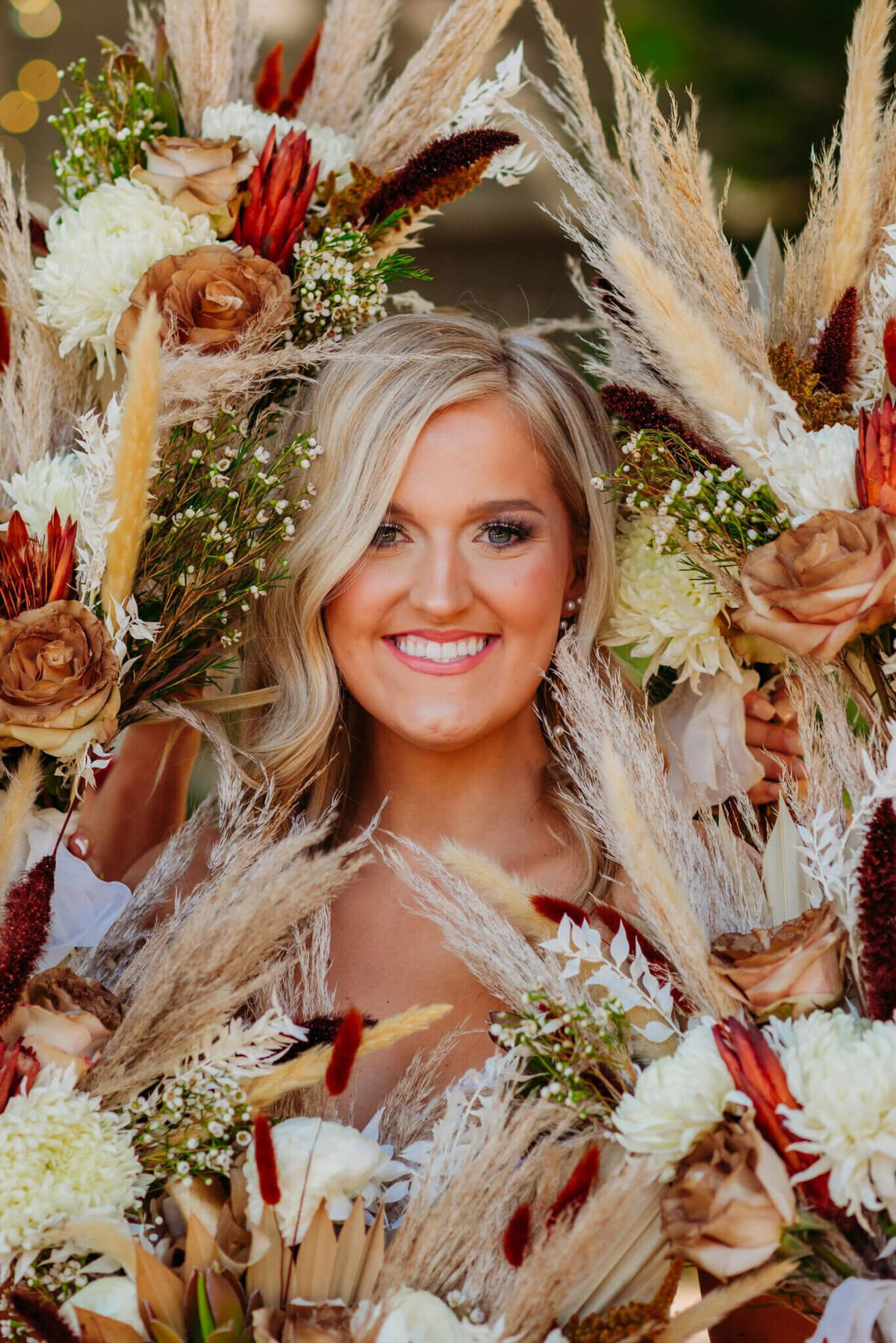 Photo of a bride smiling as she is surrounded by flowers