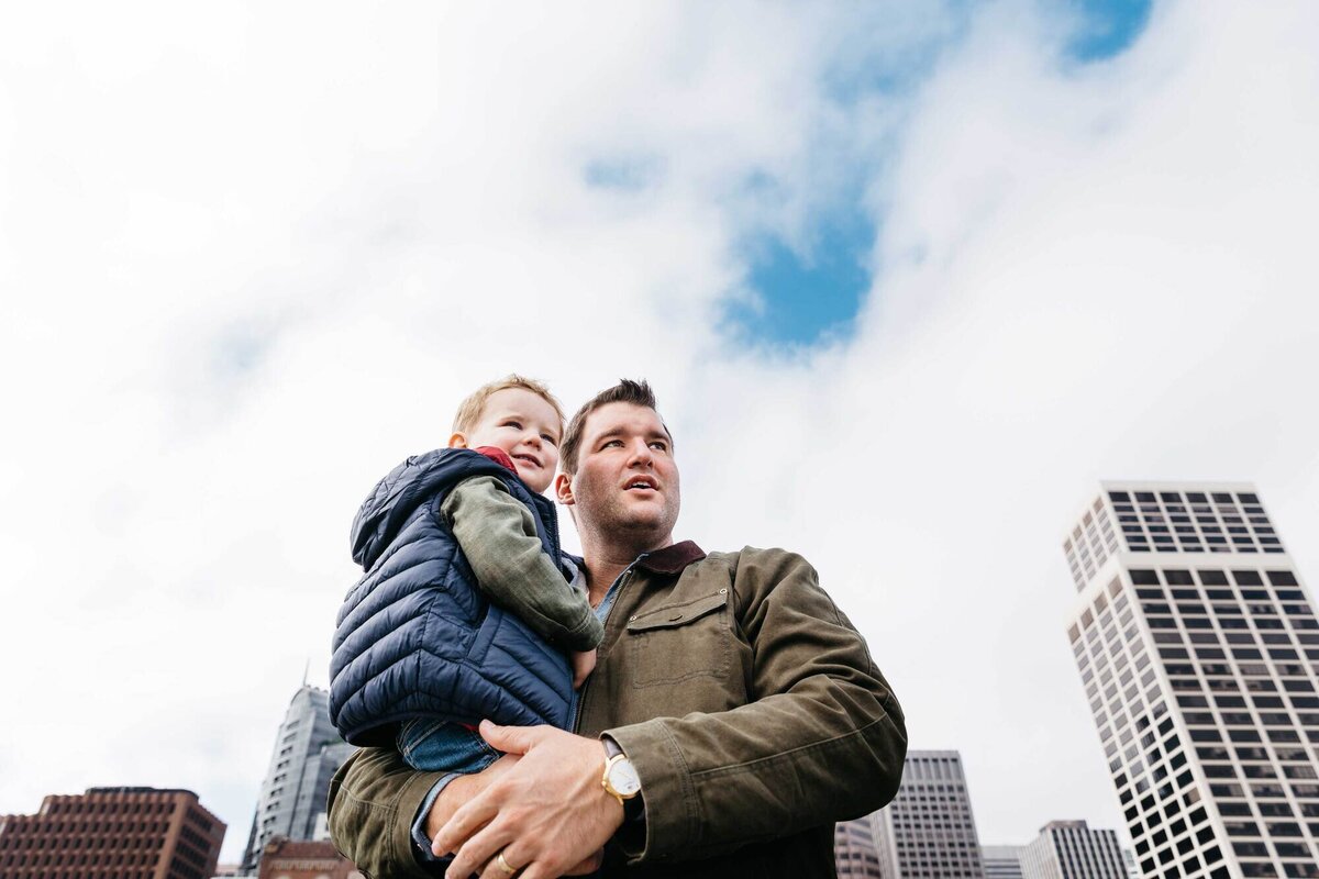 dad holding toddler son with the san francisco skyscrapers in the background.