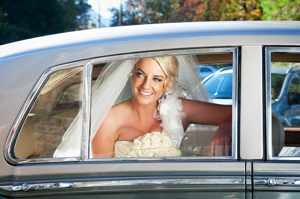 blonde bride looking out the window of her vintage Rolls Royce wedding car in Kerry