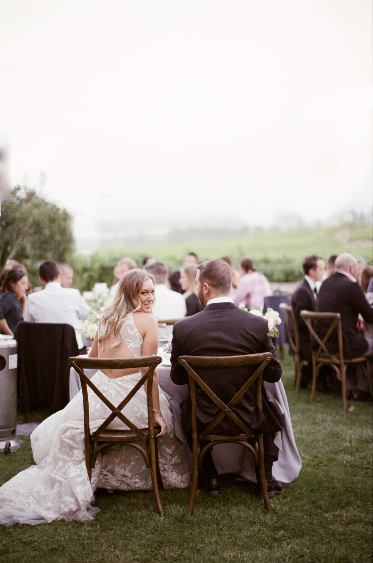Wine Country Destination Wedding Photographer Robin Jolin photographs a wedding reception party with the groom in a suit and bride wearing a semi-nude wedding gown.