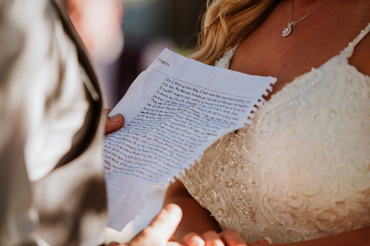 groom reading his personal written vows to bride during wedding ceremony