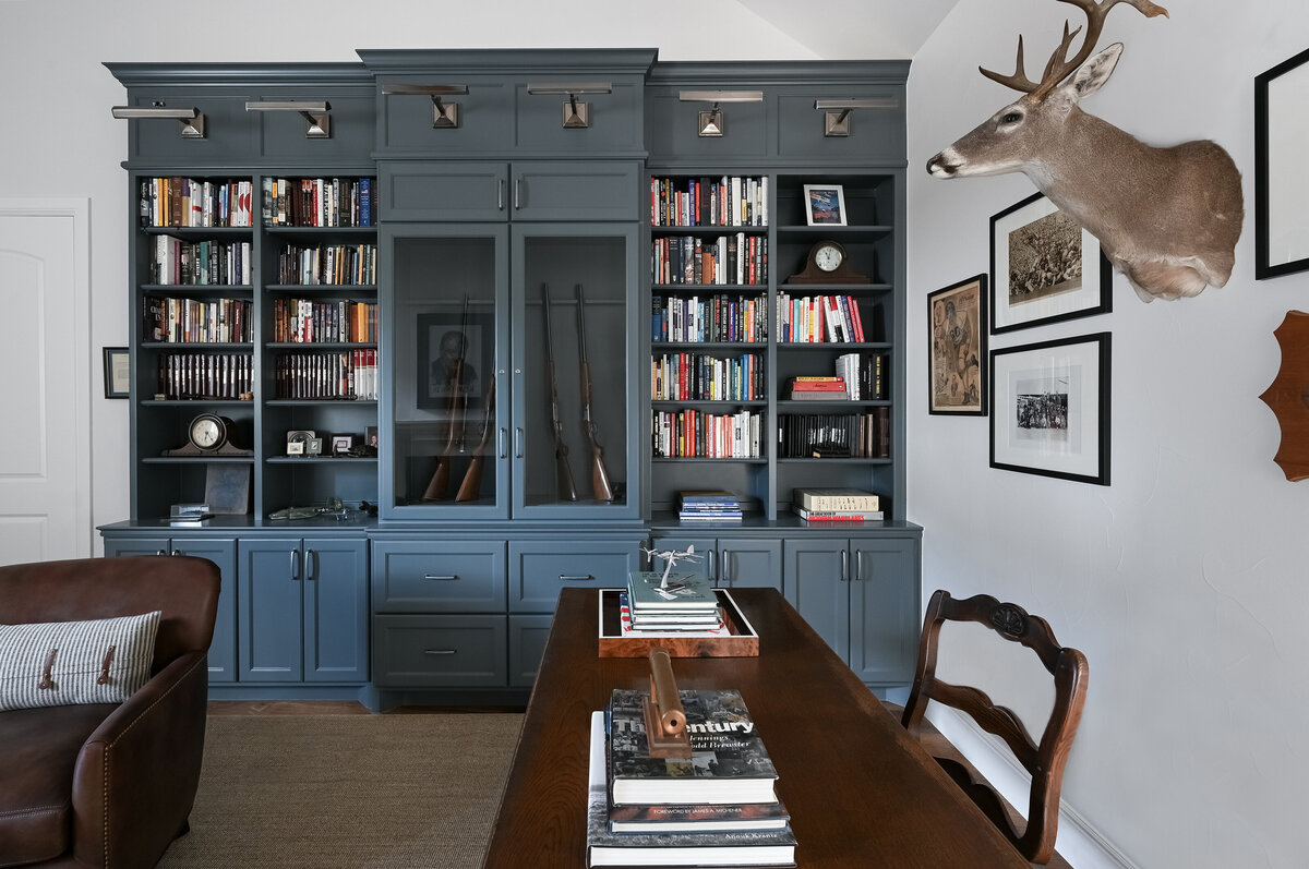 home library shelving with hunting equipment