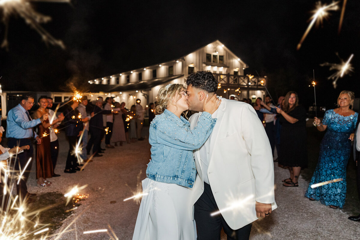 guests celebrating with sparklers as bride and groom kiss