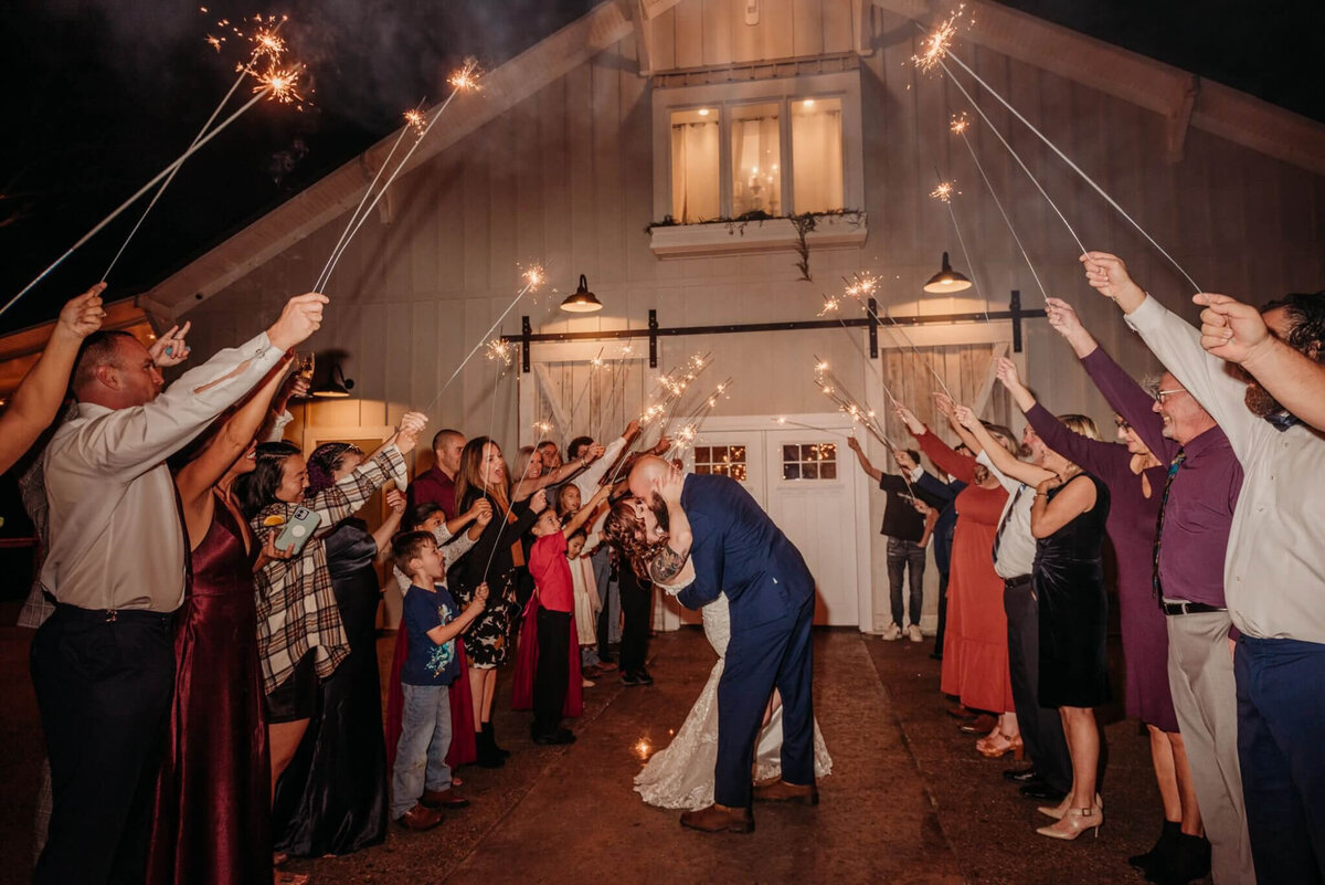 photo of a bride and groom kissing in a tunnel of sparklers