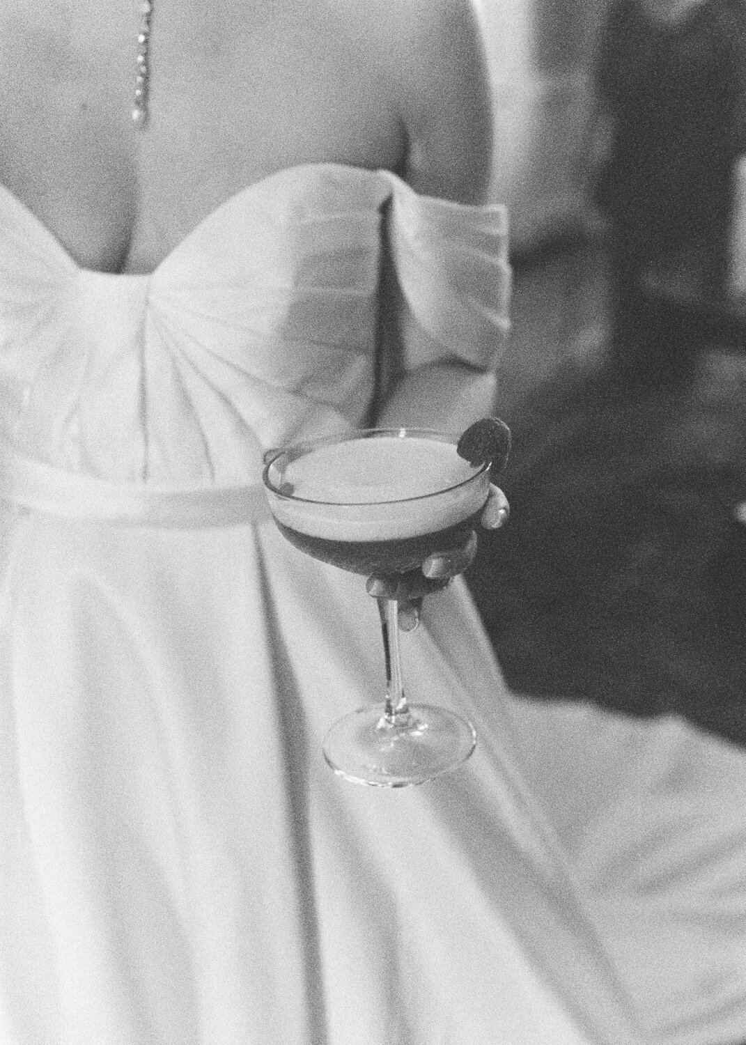 bride wear off shoulder satin wedding dress and holding cocktail glass