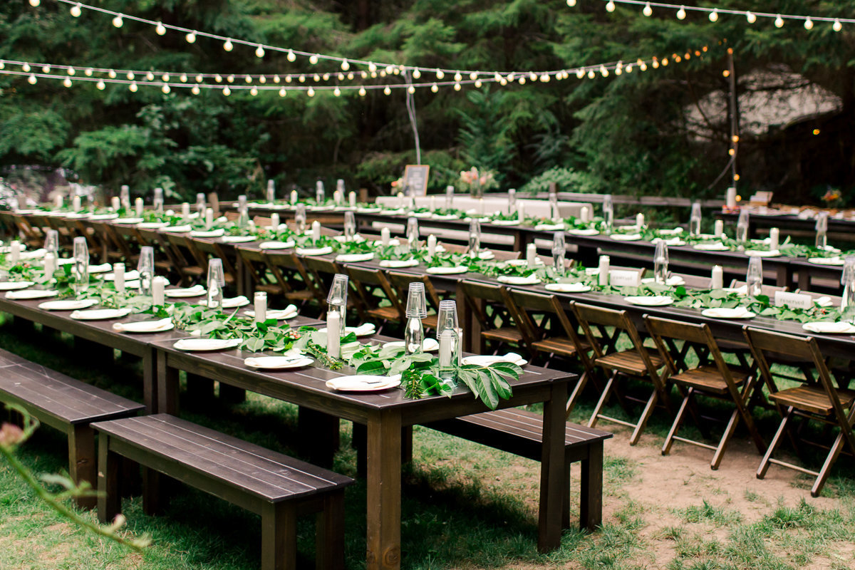 outdoor reception setup under cafe lights with wood tables and benches