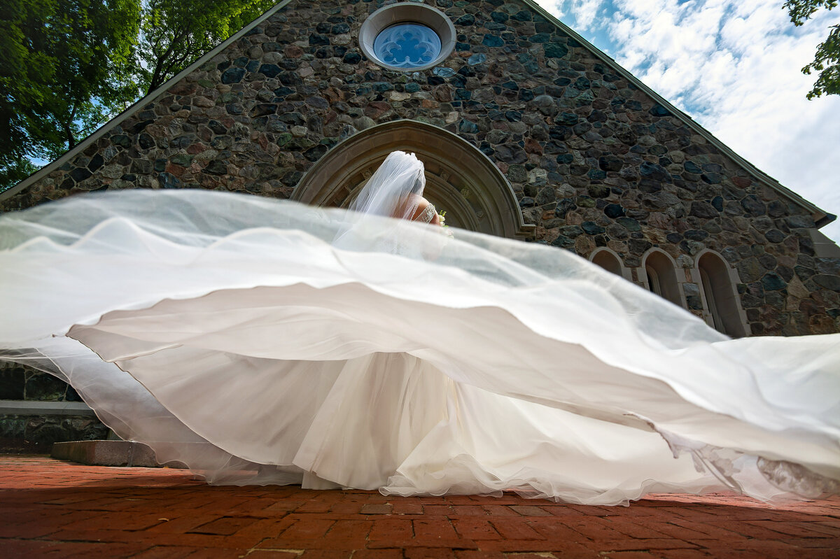 A view from below of a brides dress blowing in the wind.